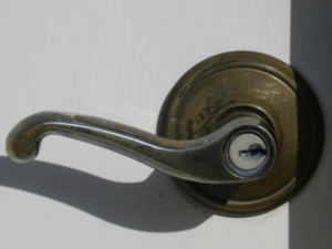 A lever-style doorknob where the user has a long metal handle that sticks back toward the door to push down and either pull or push against to open the door.