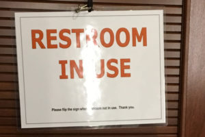 A laminated "restroom in use" sign with a footnote that said "Please flip over this sign when restroom not in use. Thank you." (On the other side, it says the restroom is not in use, with a similar footnote.) 